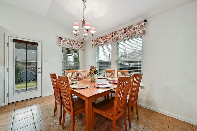 tiled dining room featuring an inviting chandelier and baseboards