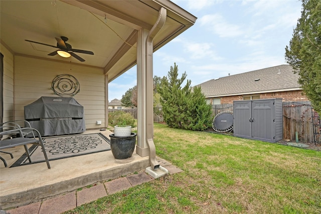 view of yard featuring ceiling fan, a storage shed, an outdoor structure, fence, and a patio area