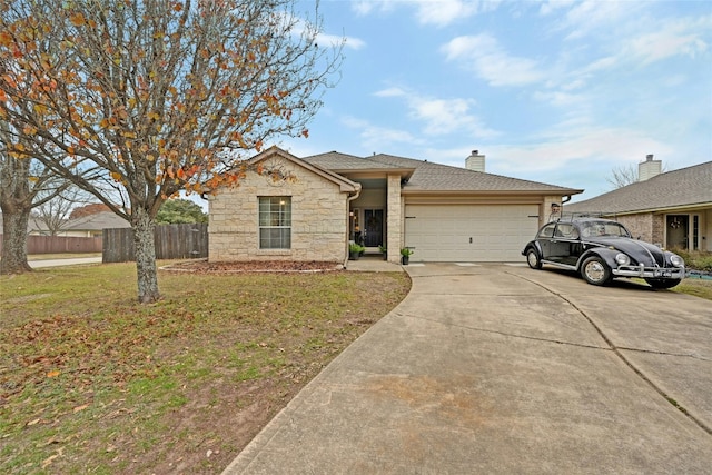 view of front of house with fence, stone siding, driveway, a front yard, and a garage