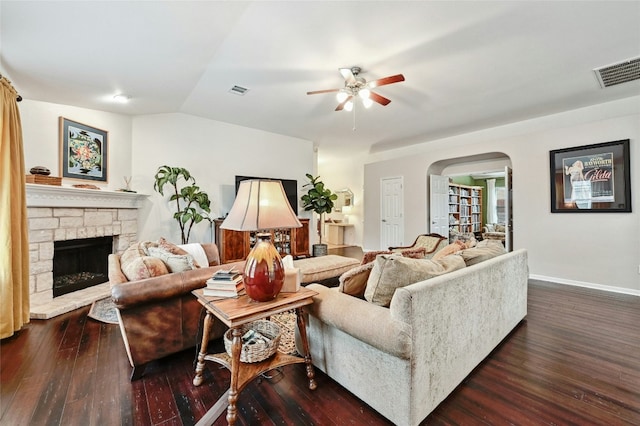 living room featuring lofted ceiling, dark wood-style floors, visible vents, and arched walkways