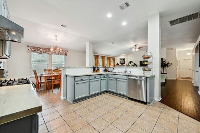 kitchen with wall chimney range hood, visible vents, and stainless steel dishwasher