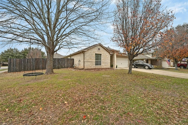 view of side of property with a yard, an attached garage, fence, stone siding, and driveway