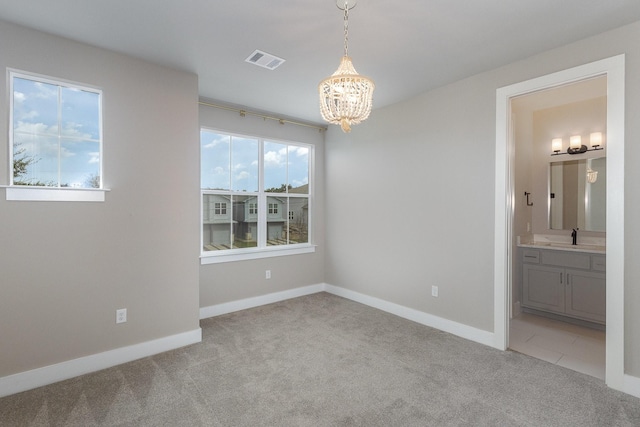 empty room with sink, light carpet, and a notable chandelier