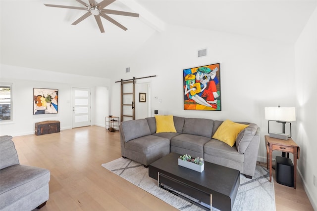 living room featuring high vaulted ceiling, ceiling fan, a barn door, beam ceiling, and light hardwood / wood-style flooring