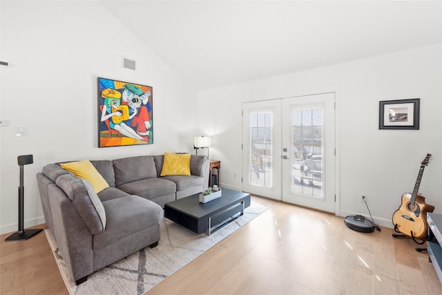 living room featuring french doors, lofted ceiling, and light hardwood / wood-style flooring