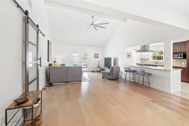 living room with high vaulted ceiling, a barn door, a wealth of natural light, and beam ceiling