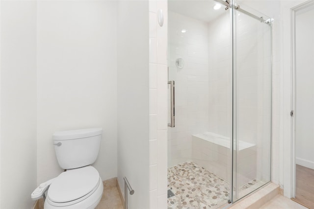 bathroom featuring toilet and a shower with door