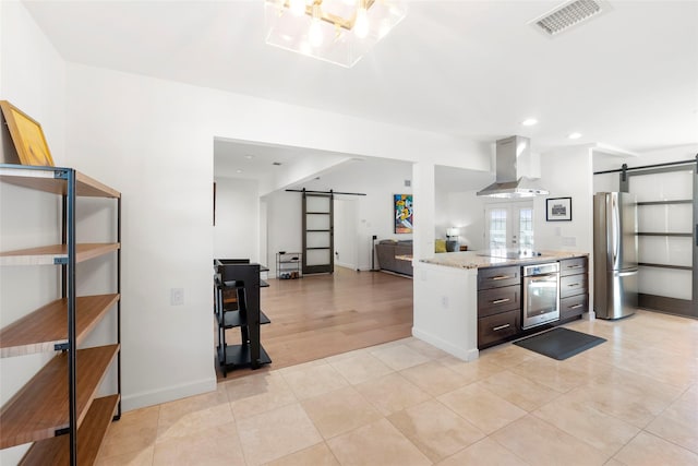 kitchen featuring light stone counters, appliances with stainless steel finishes, a barn door, and island range hood