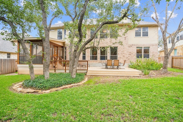 rear view of property featuring a yard, a sunroom, and a deck