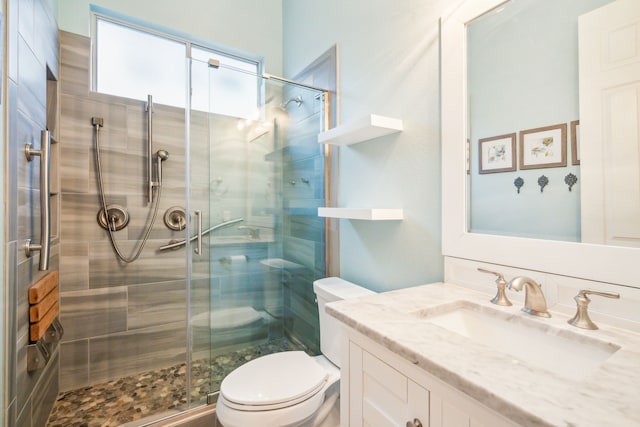 bathroom featuring vanity, a shower with shower door, and toilet