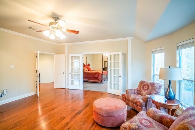 living room with crown molding, french doors, ceiling fan, and light wood-type flooring