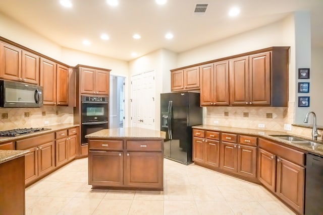 kitchen featuring sink, light tile patterned floors, backsplash, a center island, and black appliances