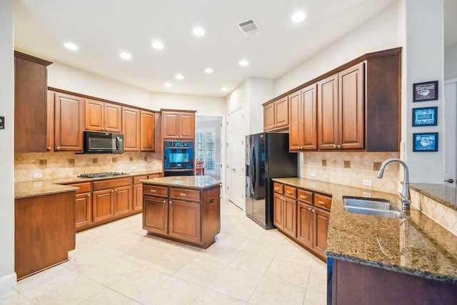 kitchen with stone countertops, sink, a kitchen island, and black appliances