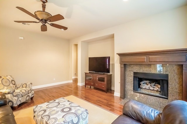 living room with ceiling fan, a premium fireplace, and light hardwood / wood-style flooring