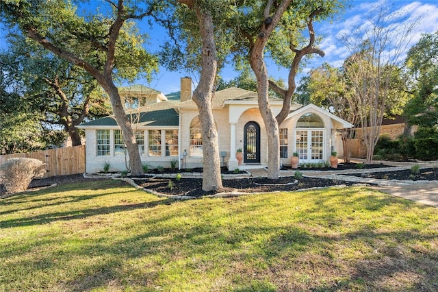 view of front of house featuring french doors, a chimney, a front lawn, and fence