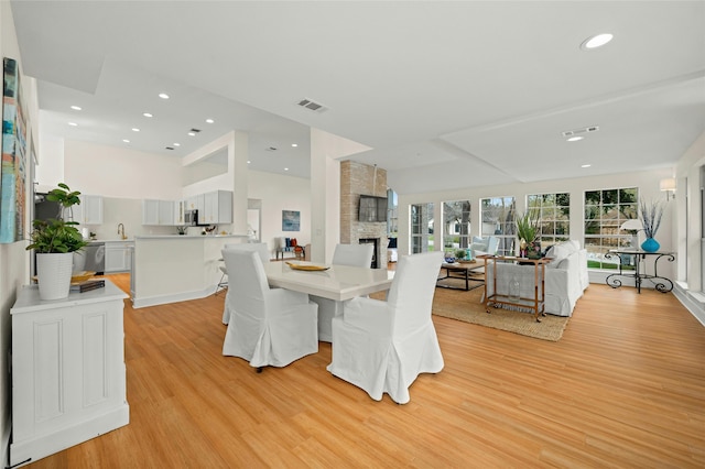 dining space featuring sink, a fireplace, and light hardwood / wood-style floors