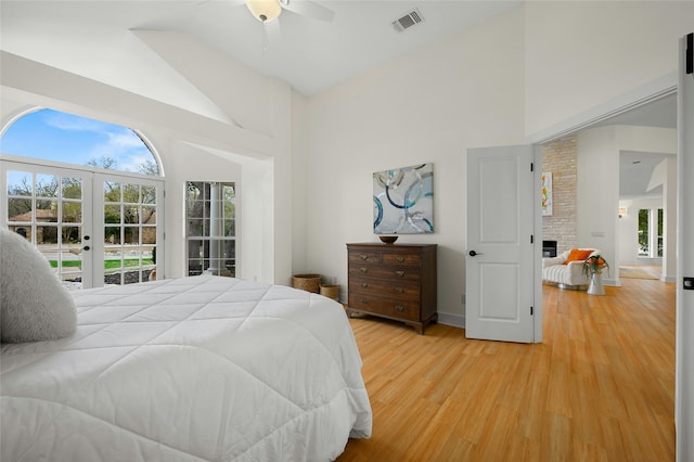 bedroom with multiple windows, a fireplace, visible vents, and light wood finished floors