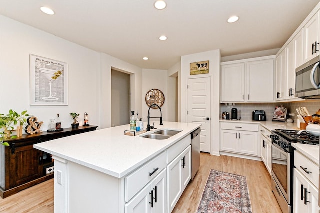 kitchen featuring appliances with stainless steel finishes, tasteful backsplash, white cabinetry, sink, and a kitchen island with sink