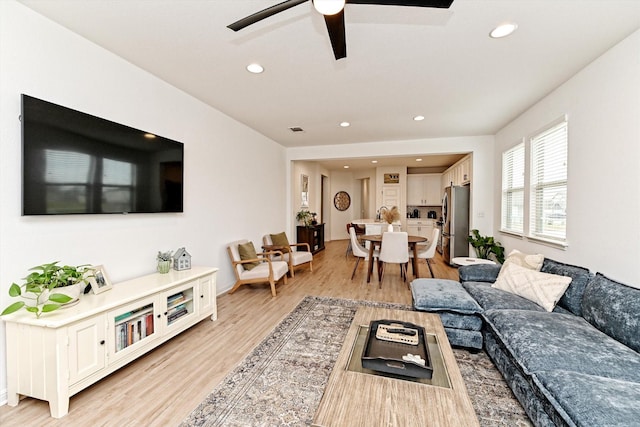 living room featuring ceiling fan and light hardwood / wood-style floors