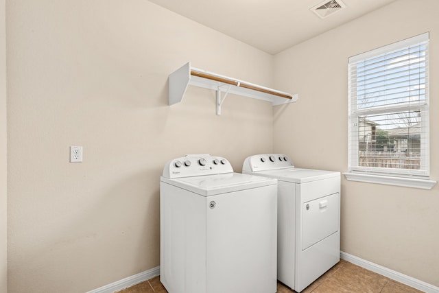 laundry area with separate washer and dryer and light tile patterned floors