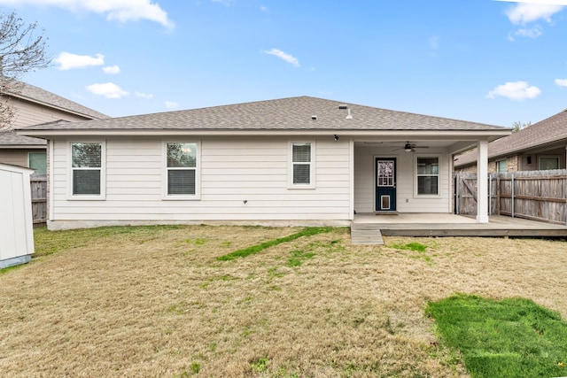 rear view of property featuring a wooden deck, ceiling fan, and a lawn