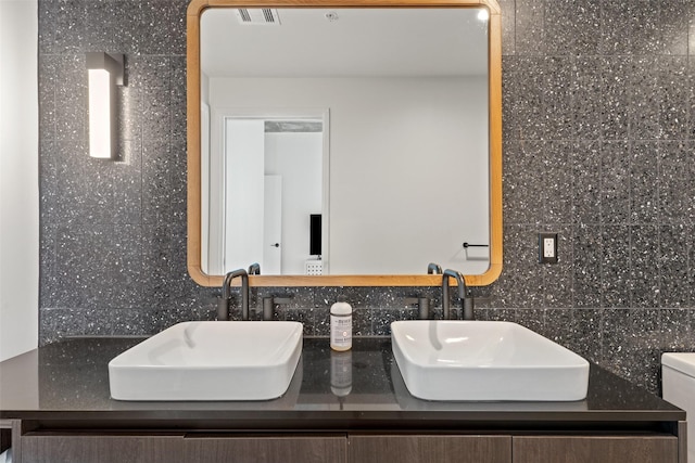 bathroom with tasteful backsplash, vanity, and tile walls