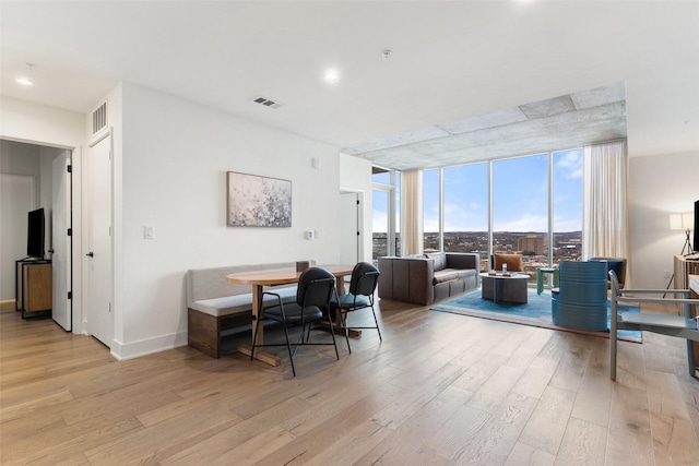 dining area with a wall of windows and light hardwood / wood-style floors