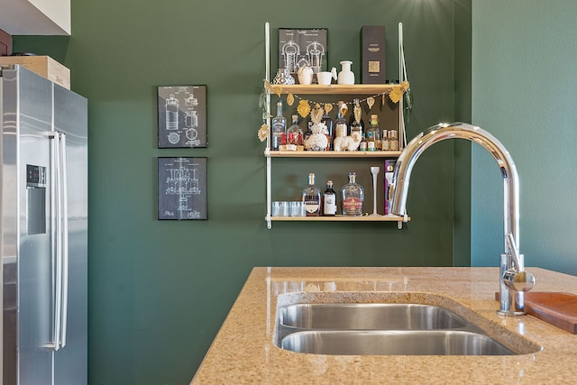 bar with stainless steel refrigerator with ice dispenser, sink, and light stone counters