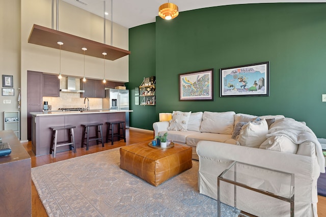 living room featuring a high ceiling, sink, and hardwood / wood-style floors