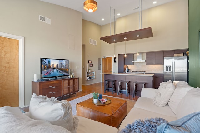 living room featuring a high ceiling, sink, and light wood-type flooring