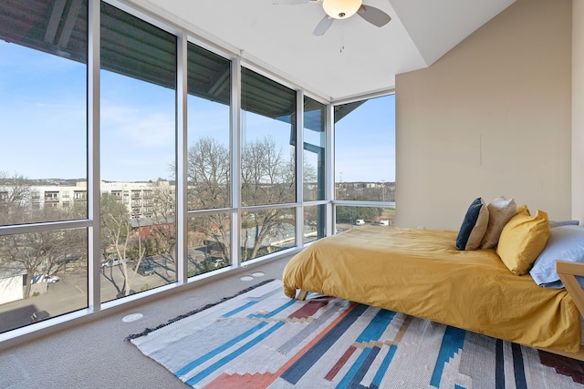 carpeted bedroom featuring multiple windows, ceiling fan, and a wall of windows