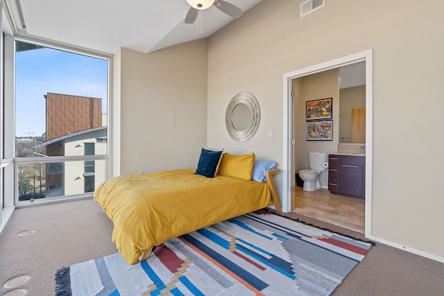 carpeted bedroom featuring floor to ceiling windows, ensuite bathroom, and ceiling fan