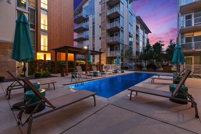 pool at dusk with a patio area