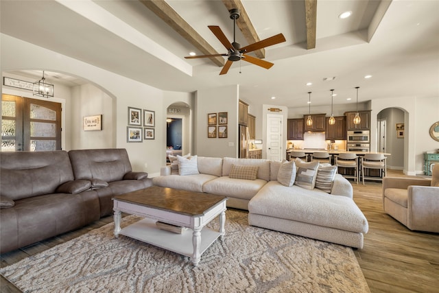 living room featuring beamed ceiling, ceiling fan, and light hardwood / wood-style floors