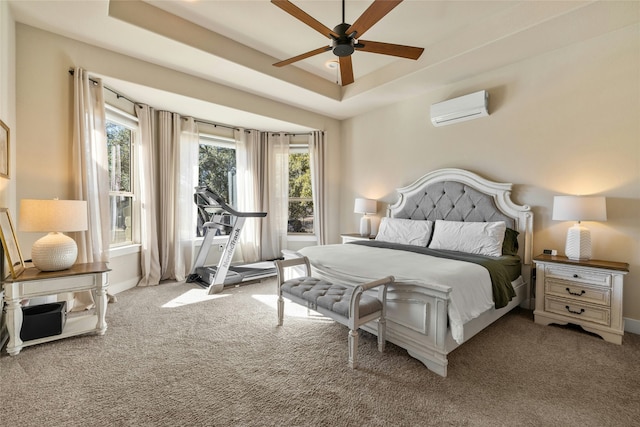 carpeted bedroom featuring ceiling fan, a wall mounted air conditioner, and a tray ceiling