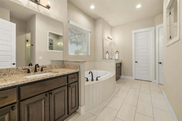 bathroom with tile patterned flooring, vanity, and a relaxing tiled tub