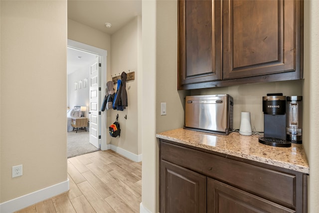 kitchen with light stone countertops, dark brown cabinets, and light hardwood / wood-style floors