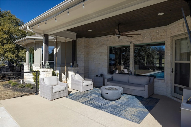 view of patio featuring ceiling fan and an outdoor living space with a fire pit