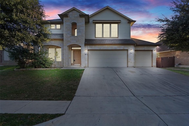 view of front of house featuring a lawn, concrete driveway, stone siding, an attached garage, and fence