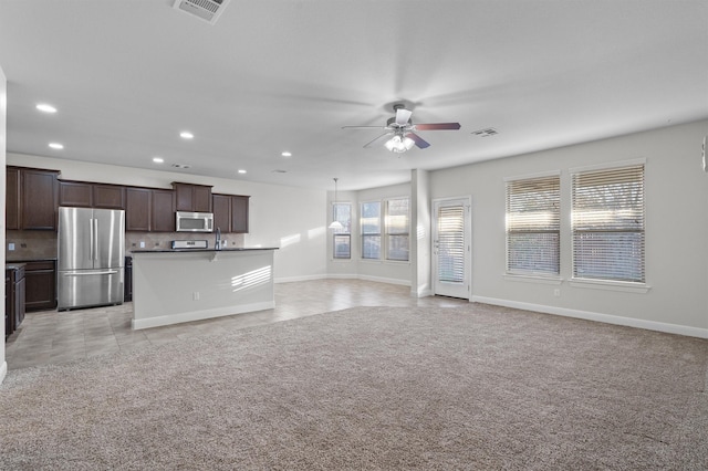 unfurnished living room featuring light tile patterned floors, visible vents, a ceiling fan, and light colored carpet