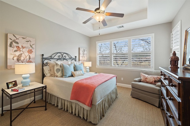 carpeted bedroom featuring ceiling fan and a tray ceiling