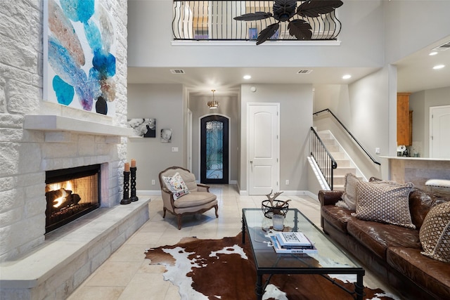 tiled living room featuring a stone fireplace, a towering ceiling, and ceiling fan