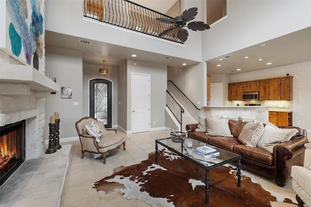 2007 Big Horn Dr, Austin, TX 78734 - living room featuring a ceiling fan, stairs, light tile patterned floors, a stone fireplace, and a high ceiling