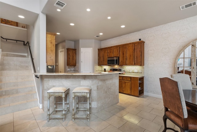 kitchen featuring light tile patterned floors, a breakfast bar area, and kitchen peninsula