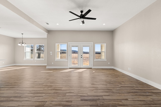 unfurnished living room with french doors and ceiling fan with notable chandelier