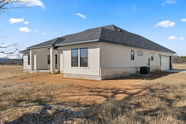 rear view of house with a garage and central AC