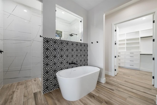 104 Cactus Cor, Horseshoe Bay, TX 78657 - bathroom with walk in shower, a walk in closet, a soaking tub, wood finished floors, and tile walls