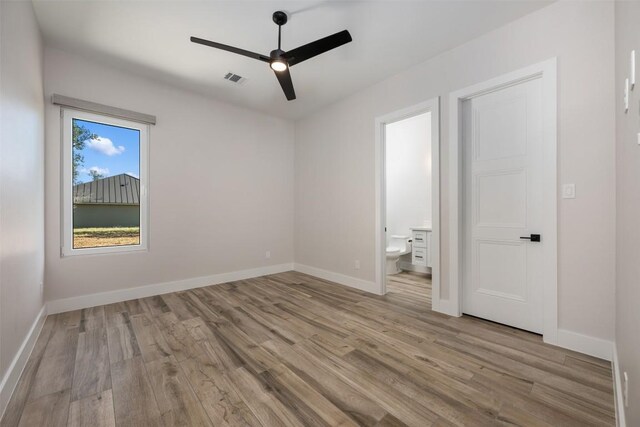 104 Cactus Cor, Horseshoe Bay, TX 78657 - unfurnished bedroom with wood finished floors, baseboards, connected bathroom, and a ceiling fan