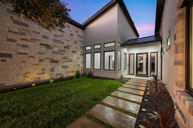 back house at dusk with a lawn