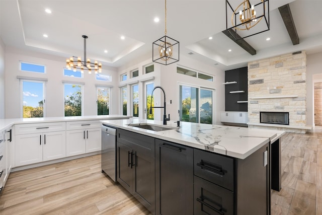 kitchen with pendant lighting, stainless steel dishwasher, sink, and a center island with sink